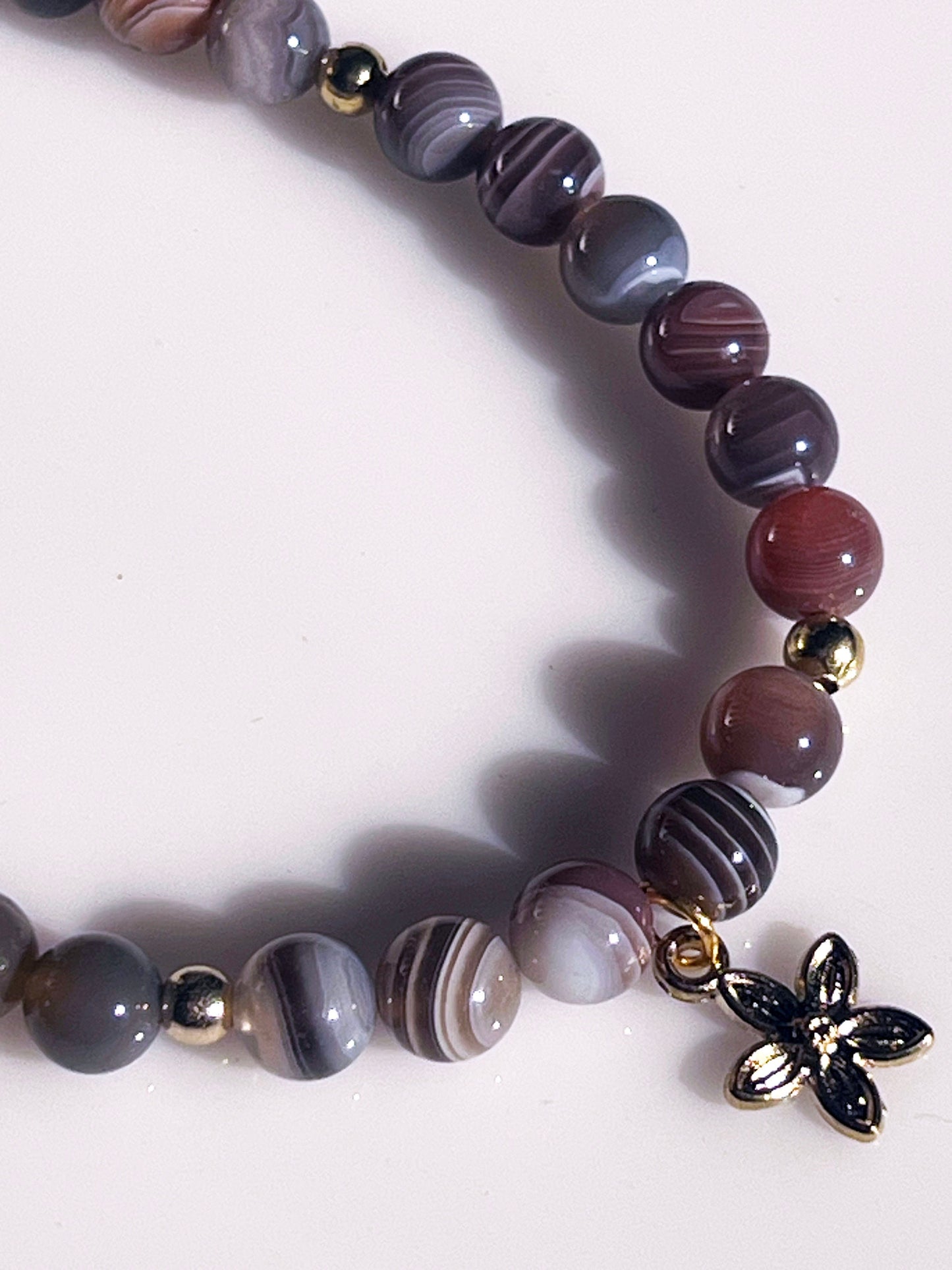 Botswana Gemstone Bracelet - Brown Botswana beaded bracelet with golden spacers and hanging flower golden charm.
