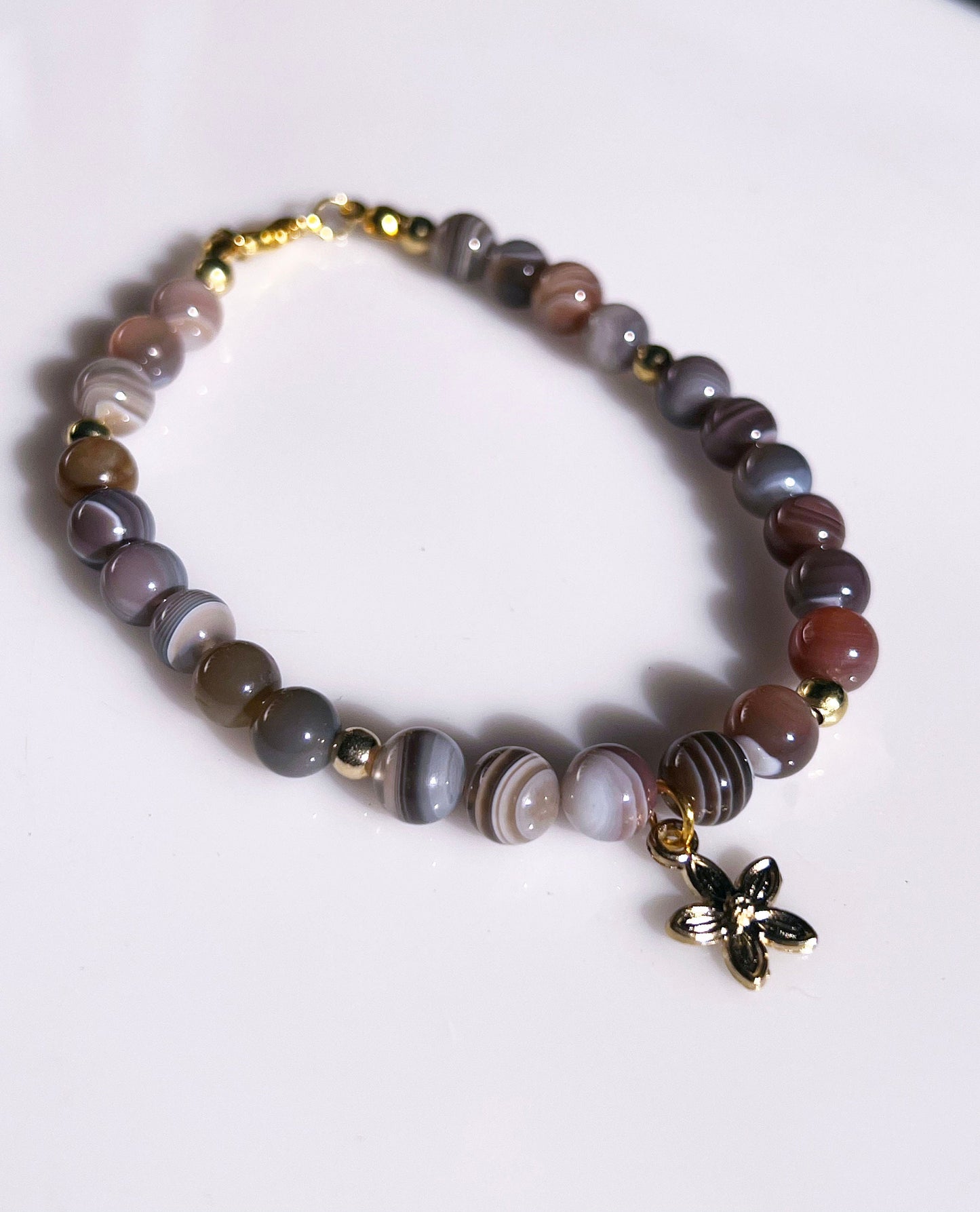 Botswana Gemstone Bracelet - Brown Botswana beaded bracelet with golden spacers and hanging flower golden charm.